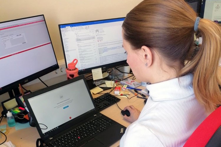 Slika Službenica katastarskog ureda sjedi za stolom uz otvoreni ekran laptopa na kojem prati on line edukaciju