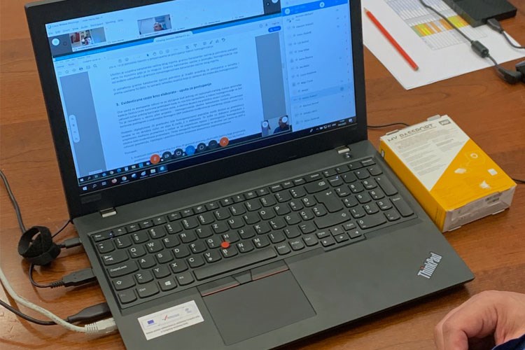Slika Otvoreni laptop s edukacijskim materijalima na ekranu uz prikazane ruke osobe koja gleda edukaciju
