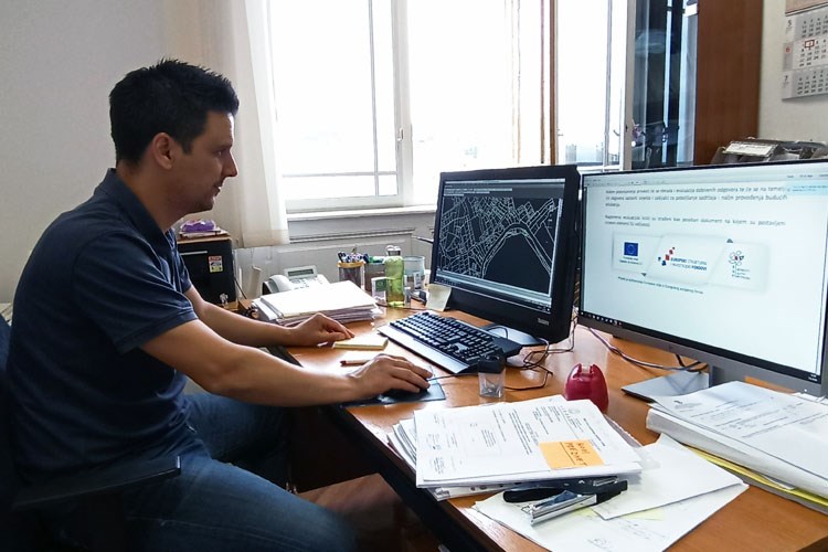 Slika Službenik katastarskog ureda sjedi za računalom i prati on line edukciju